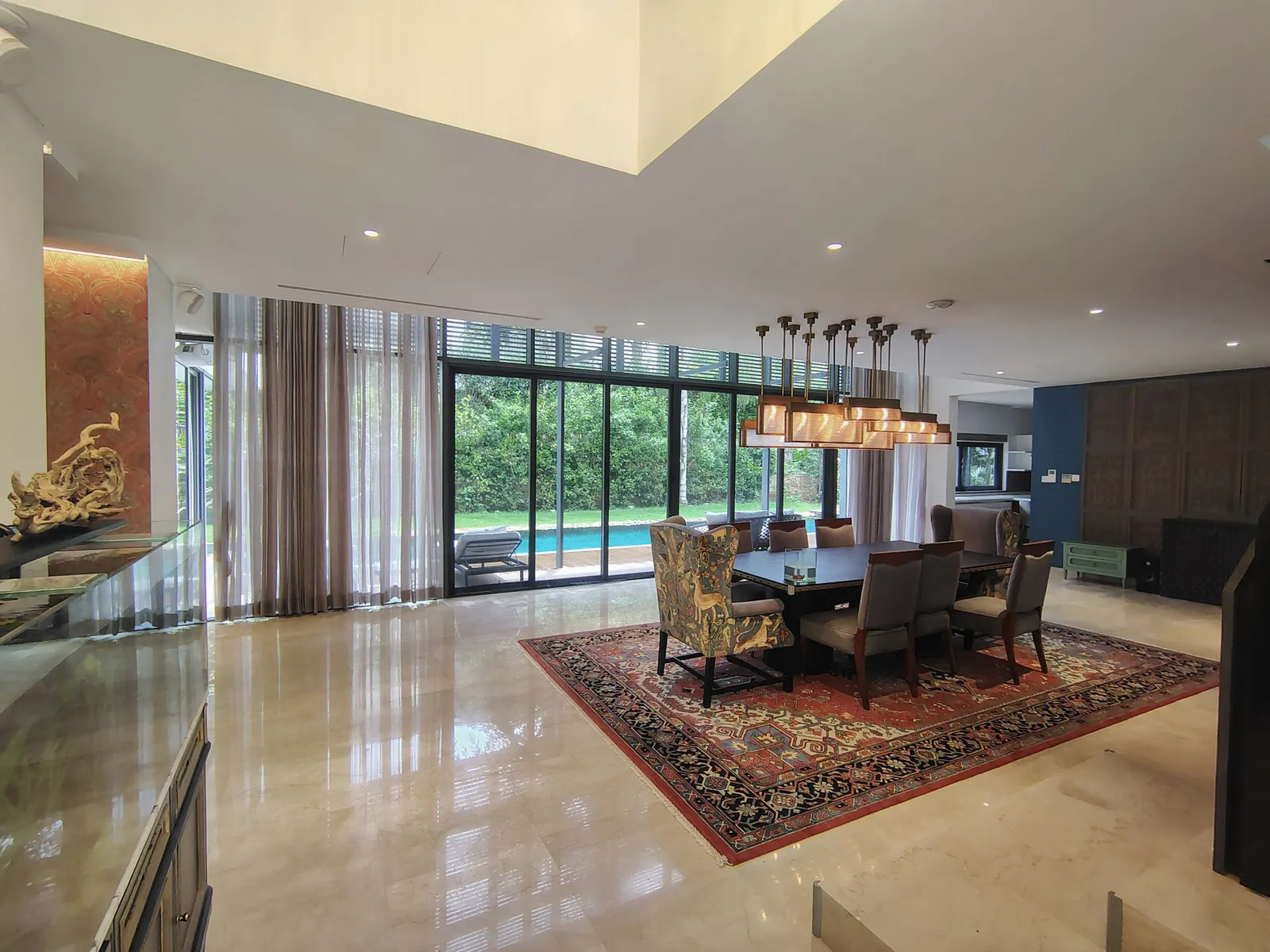 A spacious modern villa living and dining area opening to a garden and pool in North Bangalore